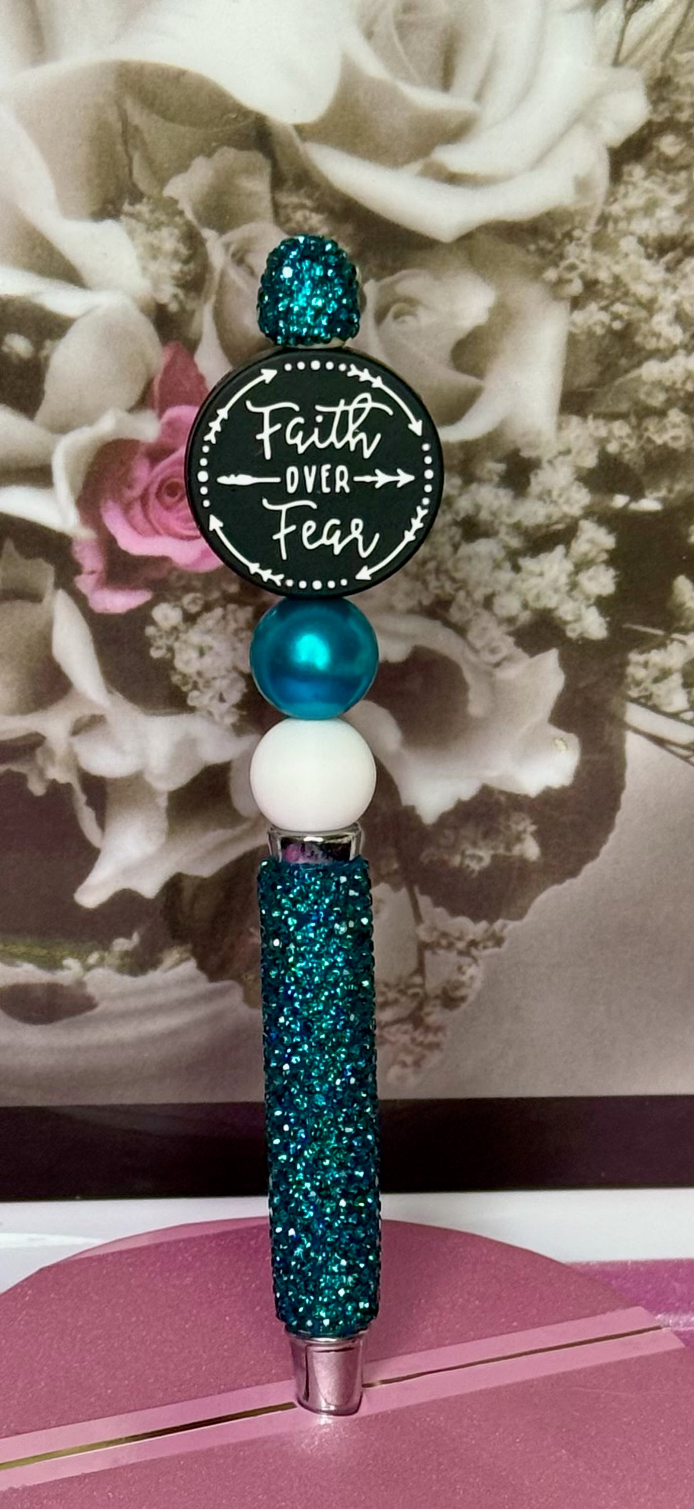 Decorative pen with 'Faith Over Fear' quote against a floral background