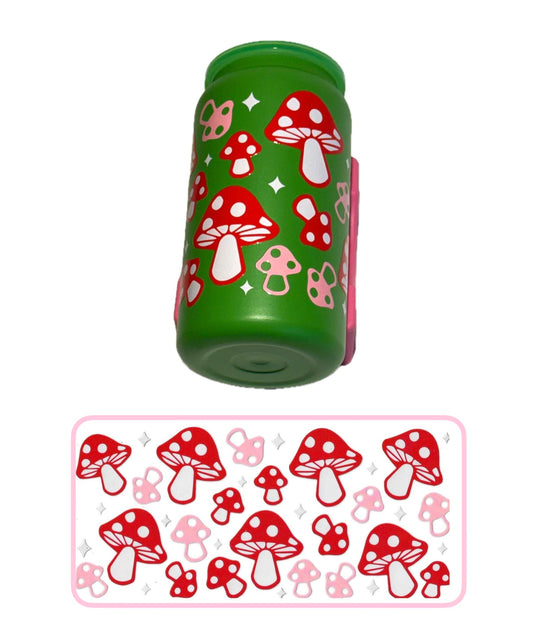 A green cylindrical container or cup with a red, white, and pink mushroom pattern, shown above a matching flat sheet of the same mushroom decals or stickers on a white background.