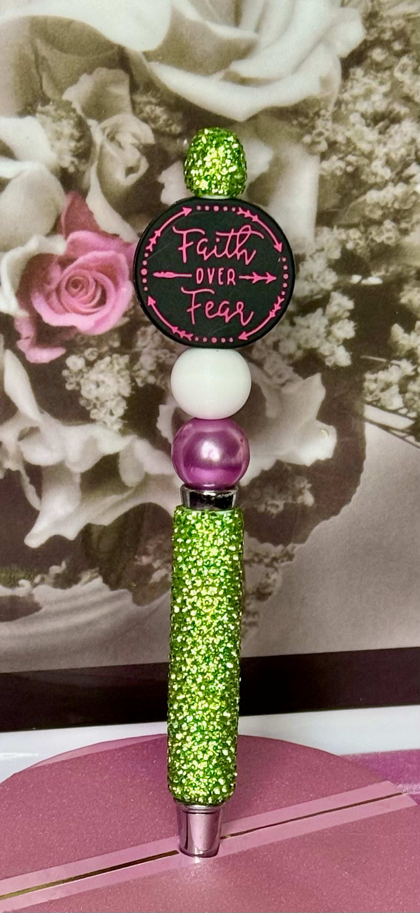 Decorative pen with 'Faith Over Fear' quote on a floral background